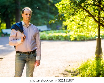 handsome guy in a jacket on a background of tree crowns in the park at sunset