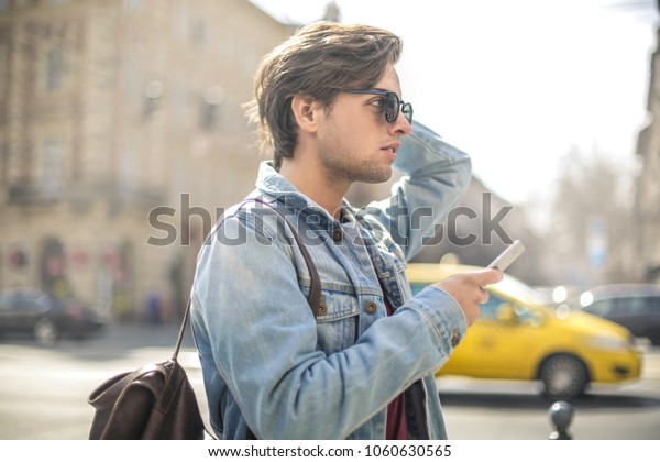 Handsome\
guy looking around the city, looking his\
phone