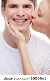 Handsome guy looking at camera with pretty girl kissing him
