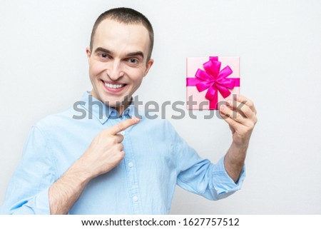 Handsome guy points to the gift that he chose for his girlfriend, portrait, white background