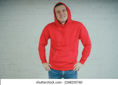 Handsome guy posing by a brick wall. Crazy man in a red hoodie - Powered by Shutterstock