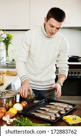 Handsome guy pouring oil in raw fish on roasting pan at  kitchen  - Shutterstock ID 172883762