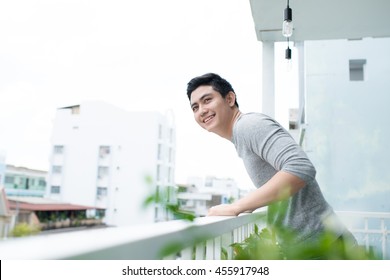 Handsome guy relaxing on a balcony, isolated on a city background