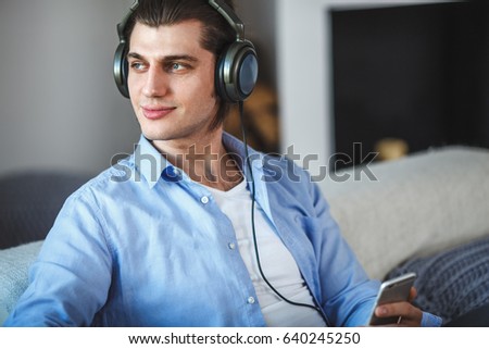 Handsome guy sitting on sofa with headphones