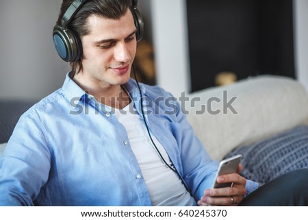Handsome guy sitting on sofa with headphones