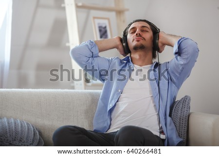 Handsome guy sitting on sofa with headphones