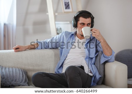 Handsome guy sitting on sofa with headphones