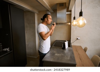 Handsome guy smelling the aroma of freshly brewed arabica espresso, enjoying his morning coffee at home. Start your happy day with a cup of freshly brewed espresso coffee - Powered by Shutterstock