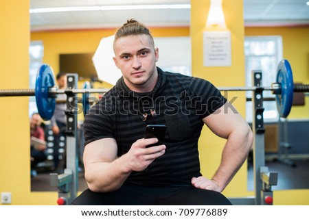 Handsome guy text messaging on his smartphone at gym.