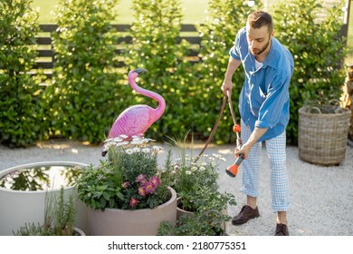 Handsome Guy Watering Flowers At Garden. Husband Take Care Of Green Plants At Backyard Of His House On Summer Time