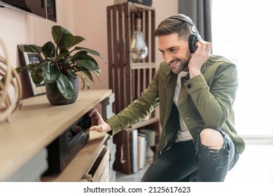 A Handsome guy wearing headphones enjoys music in front of his stereo system