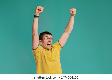 Handsome guy in a yellow casual t-shirt is posing over a blue background. - Shutterstock ID 1474364138
