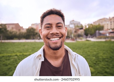 Handsome happy African American bearded man. Portrait of cheerful young man standing outdoors and smiling at camera. Positive emotion concept of male person. Generation z guy look carefree and natural