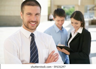 Handsome Happy Business Man With Colleagues At The Back