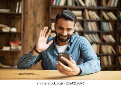 Handsome Happy Hispanic Guy Using Smartphone For Video Connection, Making Video Call To Friends Or Family, Cheerful Indian Man Looks At The Phone Webcam, Waving And Greeting Online Interlocutor