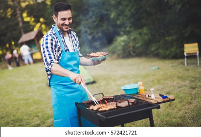 Handsome  happy male preparing barbecue outdoors for friends