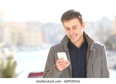 Handsome happy man smiling walking and using smart phone in winter - Powered by Shutterstock