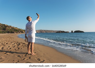 Handsome happy man in white shirt taking selfie on the beach. Summer vacations concept.  - Shutterstock ID 1640528569