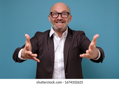 Handsome Happy Mature Italian Man With Open Hand Ready For Hugs On Blue Background. Emotions Concept