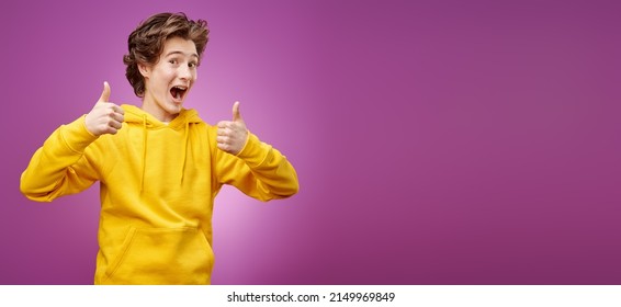A handsome, happy teenager in trendy yellow clothes cheerfully smiles and shows his thumbs up. Purple background. Youth lifestyle and emotions. Copy space. - Shutterstock ID 2149969849