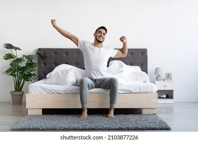 Handsome Happy Young Arab Guy Waking Up In The Morning, Sitting On Bed And Stretching After Good Sleep, Smiling Millennial Middle Eastern Man Having Good Mood, Enjoying Start Of New Day, Copy Space