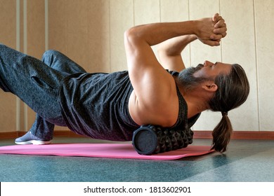 Handsome Healthy Bearded Long Haired Guy Doing An Exercise On A Mat With Foam Roller On His Upper Back. Caucasian Man With Long Hairs, Beard And Moustache Using Foam Roller Massager For Relaxation