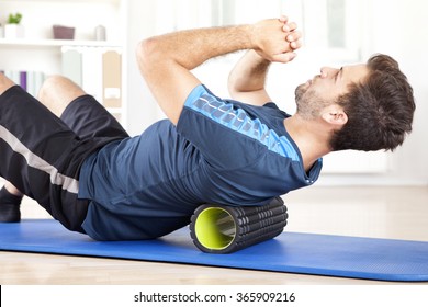 Handsome Healthy Guy Doing an Exercise on a Mat with Foam Roller on his Upper Back