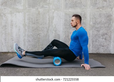Handsome healthy guy doing an exercise on a mat with foam roller on his upper back