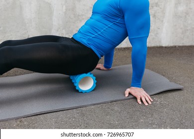 Handsome healthy guy doing an exercise on a mat with foam roller on his upper back