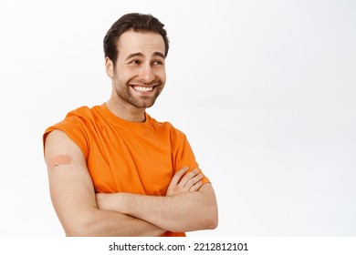 Handsome Healthy Guy Smiles, Shows Shoulder With Band Aid After Covid 19 Vaccination Shot, Vaccine Injection, Stands Over White Background