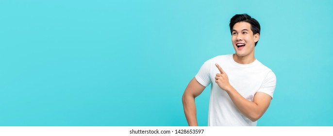 Handsome Healthy Young Asian Man Smiling With His Finger Pointing Isolated On Light Blue Banner Background With Copy Space