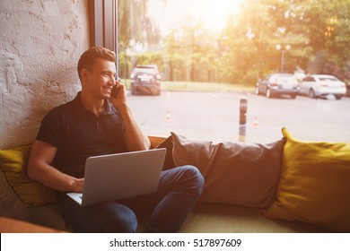 Handsome Hipster Modern Man Working Home Using Laptop Besides A Large Window With Film Flare Effect