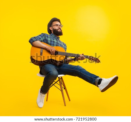 Handsome hipster musician man sitting and playing guitar. 