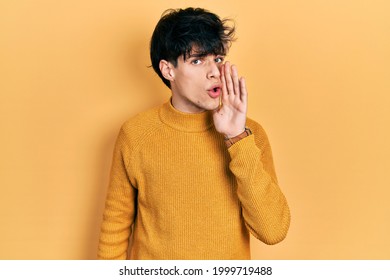 Handsome hipster young man wearing casual yellow sweater hand on mouth telling secret rumor, whispering malicious talk conversation  - Shutterstock ID 1999719488
