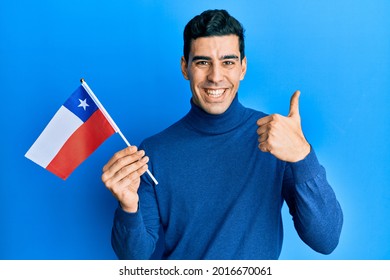 Handsome hispanic business man holding chile flag smiling happy and positive, thumb up doing excellent and approval sign 