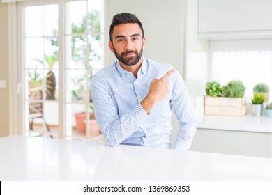 Handsome hispanic business man Pointing with hand finger to the side showing advertisement, serious and calm face - Shutterstock ID 1369869353