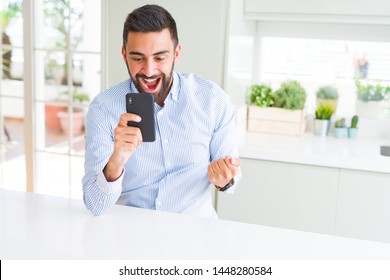 Handsome Hispanic Business Man Using Smartphone Screaming Proud And Celebrating Victory And Success Very Excited, Cheering Emotion