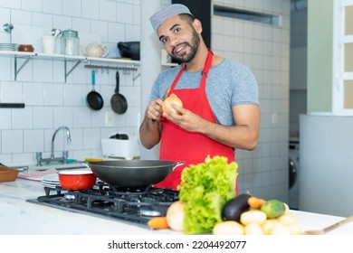 Handsome Hispanic Cook With Red Apron Preparing Food At Kitchen Of Restaurant