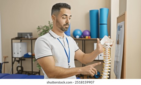 Handsome hispanic man with beard explaining spine model in a rehab clinic, portraying a professional healthcare setting. - Powered by Shutterstock