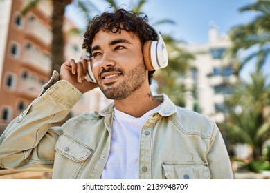 Handsome Hispanic Man With Beard Smiling Happy Outdoors On A Sunny Day Wearing Headphones