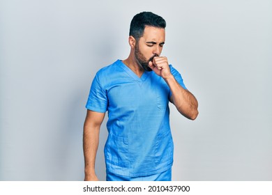 Handsome Hispanic Man With Beard Wearing Blue Male Nurse Uniform Feeling Unwell And Coughing As Symptom For Cold Or Bronchitis. Health Care Concept. 