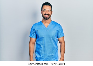 Handsome Hispanic Man With Beard Wearing Blue Male Nurse Uniform With A Happy And Cool Smile On Face. Lucky Person. 