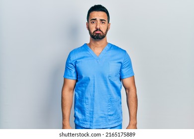 Handsome Hispanic Man With Beard Wearing Blue Male Nurse Uniform Depressed And Worry For Distress, Crying Angry And Afraid. Sad Expression. 