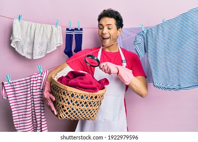 Handsome Hispanic Man Doing Laundry Holding Wicker Basket Looking For A Stain Celebrating Crazy And Amazed For Success With Open Eyes Screaming Excited. 