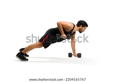 Handsome hispanic man doing push up exercises with dumbbell weights for his cross training workout