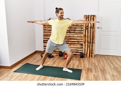 Handsome Hispanic Man Doing Warrior Yoga Pose At The Gym