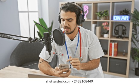 Handsome hispanic man in medical uniform podcasting with microphone and smartphone in radio studio. - Powered by Shutterstock