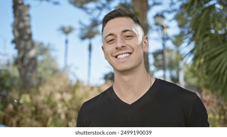 Handsome hispanic man smiling outdoors in a city park with greenery. - Powered by Shutterstock