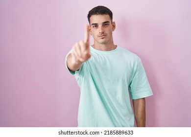 Handsome Hispanic Man Standing Over Pink Background Pointing With Finger Up And Angry Expression, Showing No Gesture 