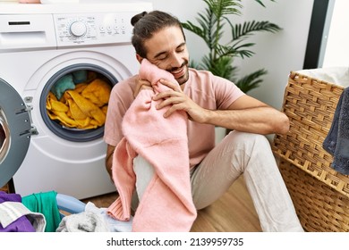 Handsome hispanic man touching soft and fresh laundry at laundry room